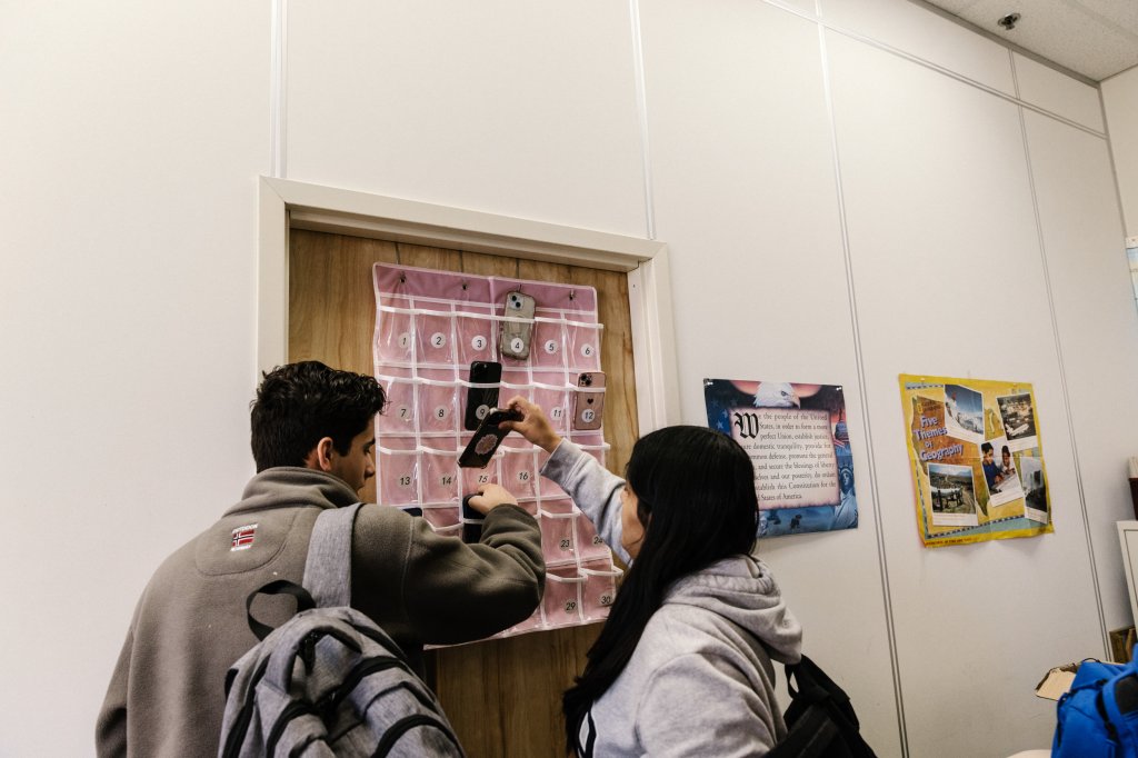 Photo of in middle school students putting phones in pouch